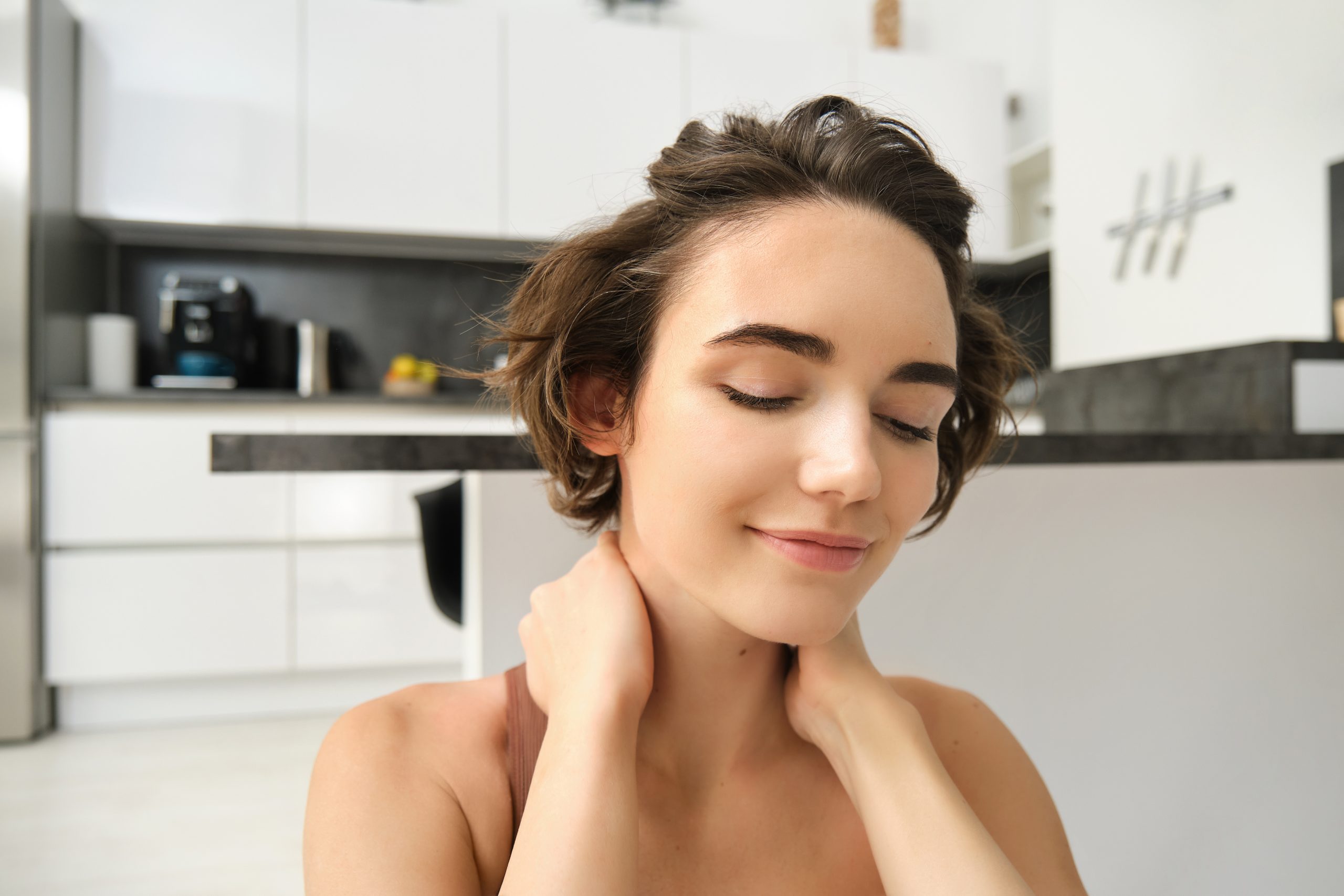 Woman touching the back of her neck, representing concern and need for remedies to get rid of black neck naturally.