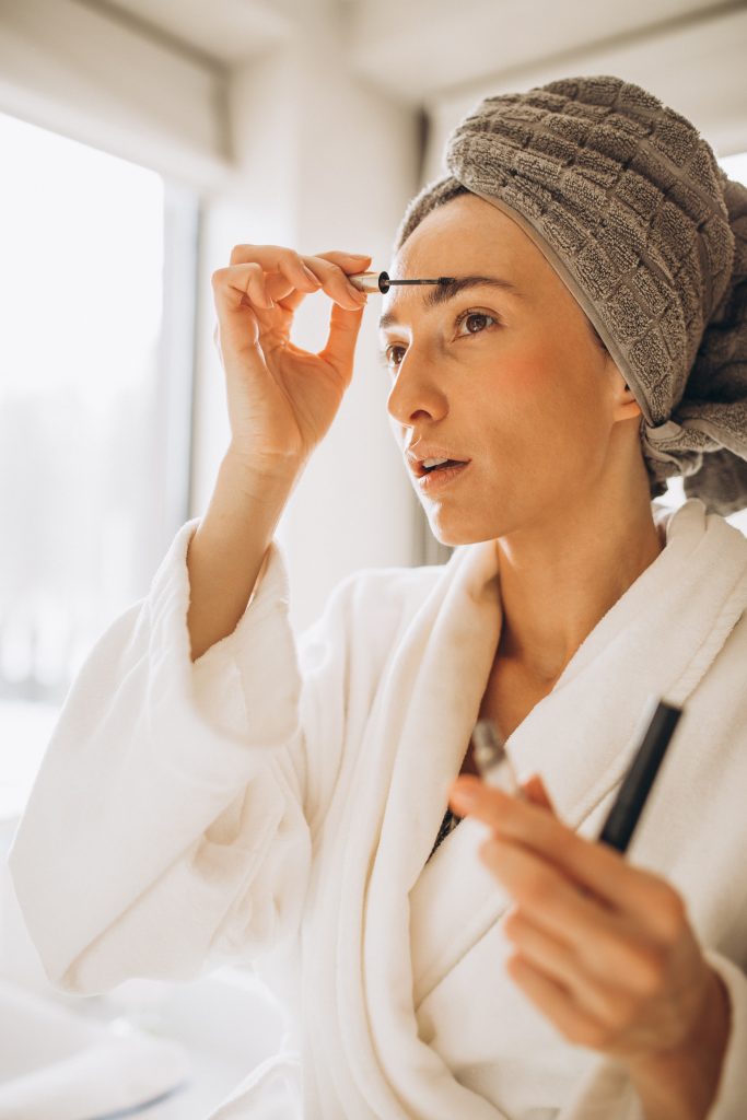 Young woman brushing her eyebrows with a spoolie brush

