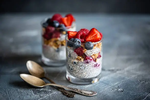 Colorful flat lay of high-fiber chia seed recipes including puddings, smoothies, and overnight oats on a marble surface, ideal for digestion and gut health.